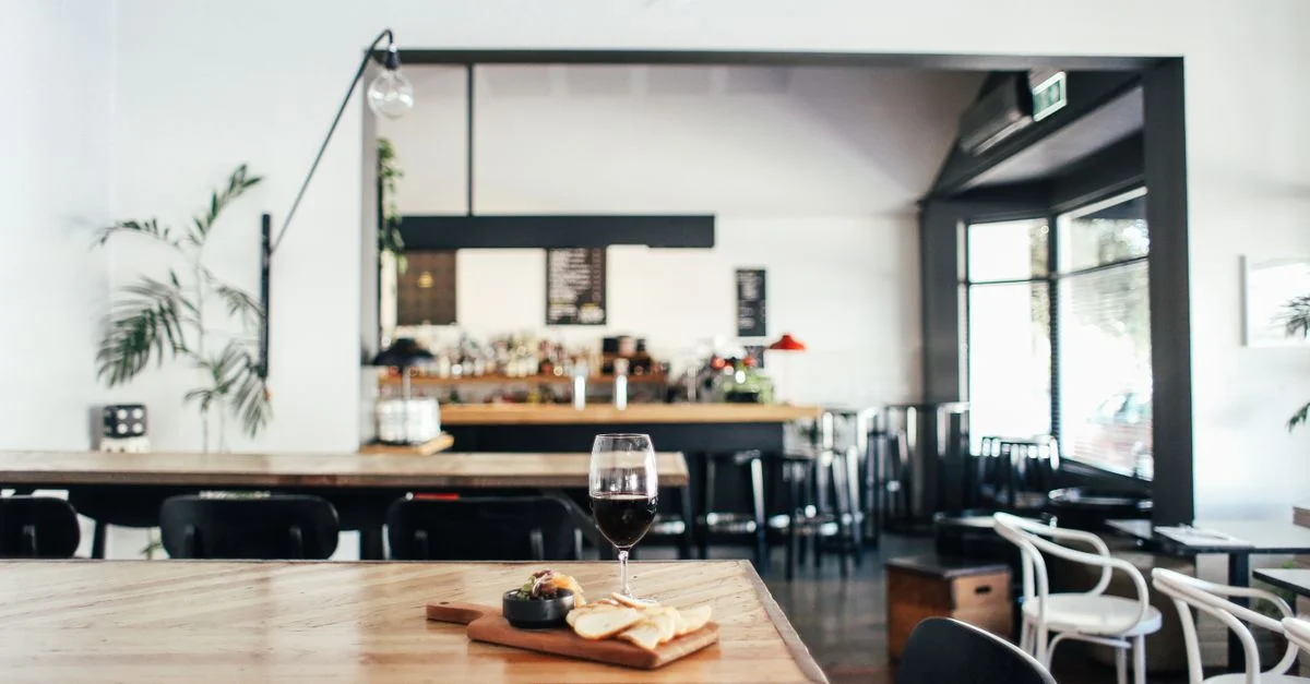 Ambiance de restaurant chaleureux avec un plateau de fromages et un verre de vin sur une table en bois rustique.