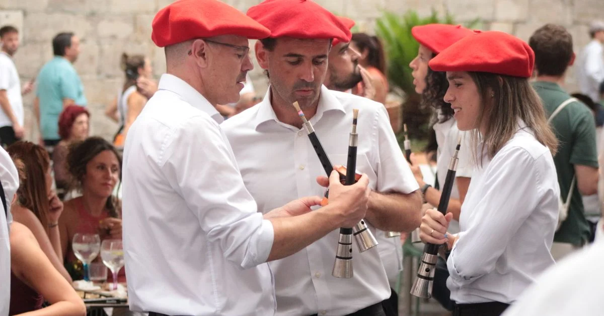 Des musiciens portant des bérets rouges jouent des instruments traditionnels lors d'un festival basque.