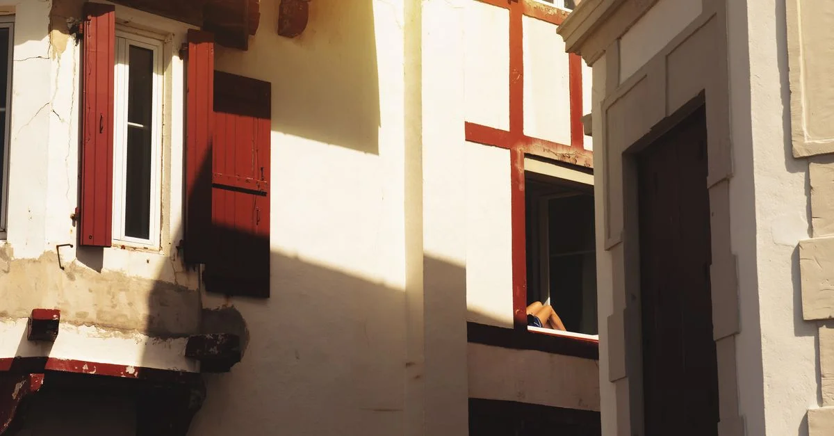 Une vue pittoresque de l'architecture basque à Saint-Jean-de-Luz avec des volets rouges et une douce lumière.