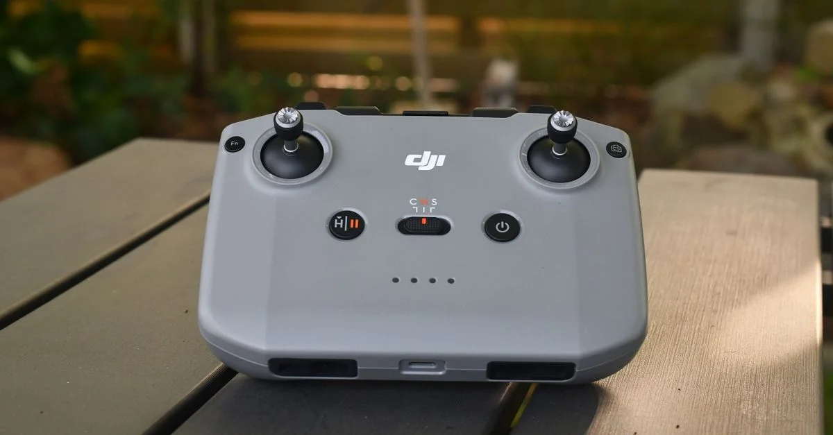 Une élégante télécommande de drone posée sur une table en bois à l'extérieur, idéale pour les passionnés de vol à distance.